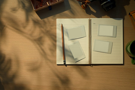 Creative workspace with vintage camera, notebook, and coffee cup in warm morning sunlight.の写真素材