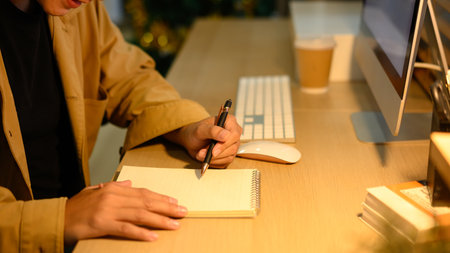 Freelancer taking notes at home desk with computer.