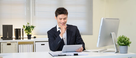 Committed smiling man looking at document data in office workplace.の写真素材