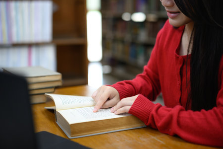 Cropped shot young girl reading book in library.の写真素材