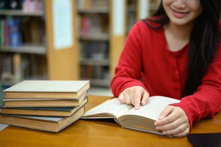 Cropped shot young girl reading book in library.