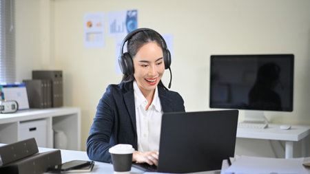 Smiling businesswoman wearing headset talking during online meeting, representing customer service...