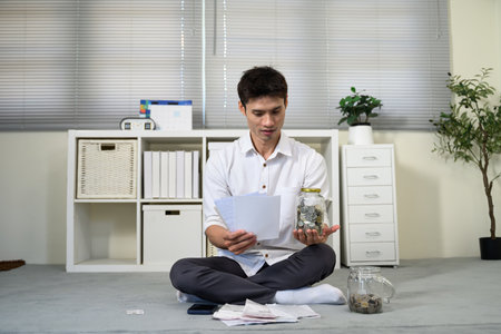 Stressed young man holding so many expenses bills in his hand no money to pay debt.の写真素材