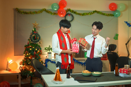 Office employees exchanging presents at work, feeling festive in office with Christmas tree and decorations..の写真素材