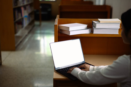 Hands holding mockup laptop in library.の写真素材