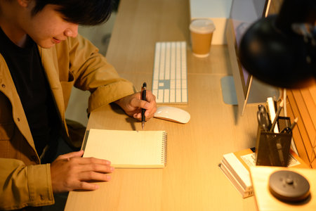 Freelancer taking notes at home desk with computer.