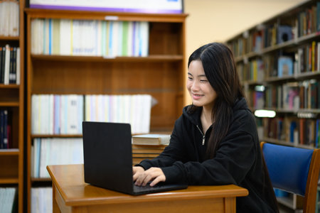 Teenage woman education or internet encyclopedia concept. Open laptop in library.