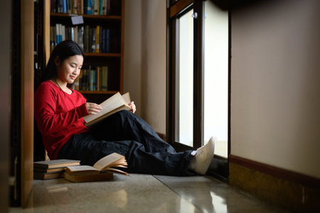 High school student girl reading book at library.