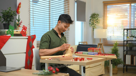 Photo set Man wrapping Christmas gifts at home with scissors and festive decorations.の写真素材