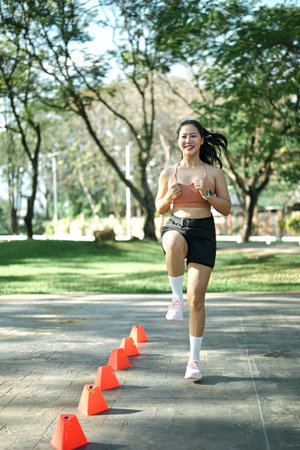 Woman doing speed and agility cone drills workout session outdoors.の写真素材