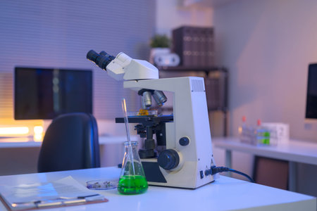Laboratory workspace with microscope, green chemical solution, and research documents, representing modern scientific analysis and controlled experimentation..の写真素材