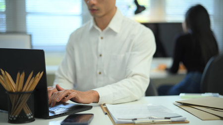 Man working on laptop at desk in modern office.