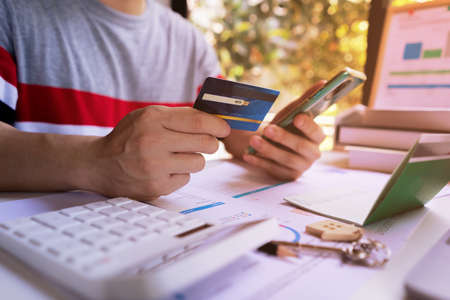 Young Man holding credit card and using mobile smartphone to Online shopping, e-commerce, internet banking, spending money. Concept of Shopping service on The online web and offers home delivery.の写真素材