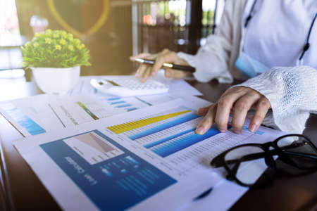 Close up businesswoman hand using calculator and pointing document about monthly expenses, managing budget, taxes statistic at home office.の写真素材