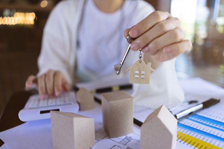 Professional Real estate agents showing house keys and calculate the price of house to customers with the model houses, house design documents.の写真素材