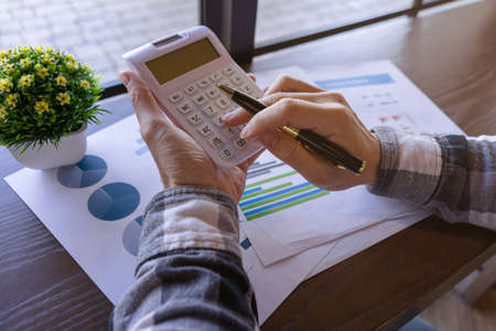 Businessman or Young freelance working with pen and pressing the calculator to calculate the accuracy of the investment budget. Freelance at work concept.の写真素材
