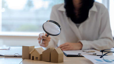 Assessor woman or realtor agents use a magnifying glass to checking house model. Concept of real estate and house appraisal.の写真素材