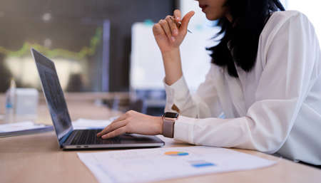 An office lady or bank officer is working hard on the laptop computer on company statistics, income,...