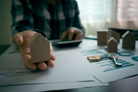 Real estate agents showing miniature house models to the customers and calculate price of house on table with key, house design document. Business Signing a Contract Buy or sell concept.の写真素材