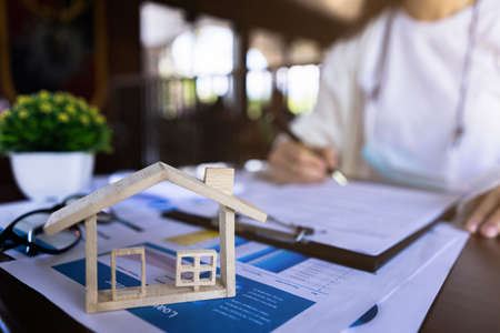 The customer is signing the house purchase contract with house model, price of house paper, contract agreement. Concept for real estateの写真素材