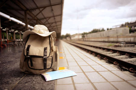 Travel backpack, hat, Traveler map near railway at the train station. Vintage Travel concept. background railroad.の写真素材