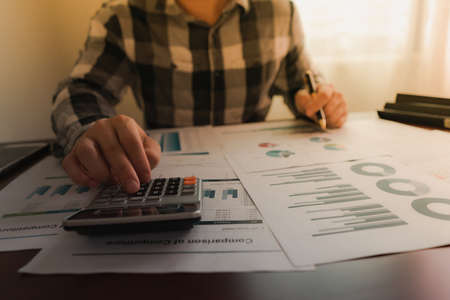 Businessman using calculator and reading chart statistics income in the workplace.の写真素材