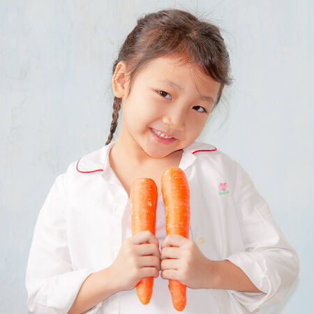 asian little girl hold and eat carrotの写真素材