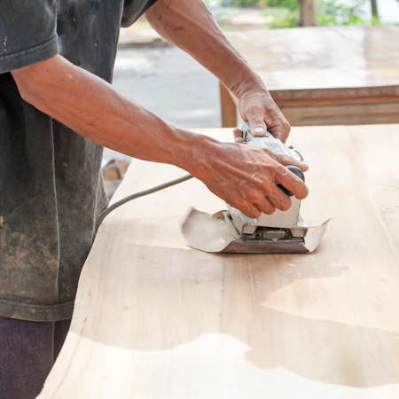 Hand of worker sanding the old wood table.