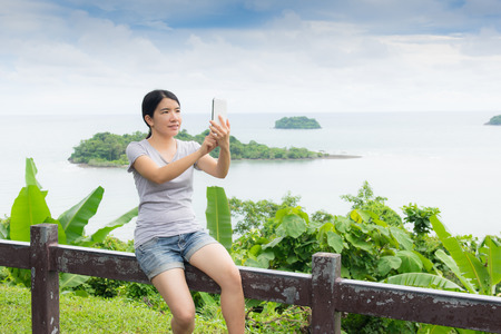 asian woman selfie with seascape against blue skyの写真素材