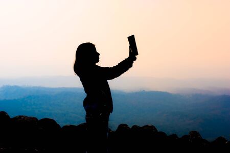 young woman selfie during Sunset on mountain with landscape view