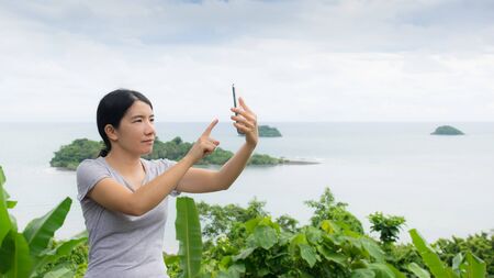 asian woman selfie with seascape against blue skyの写真素材