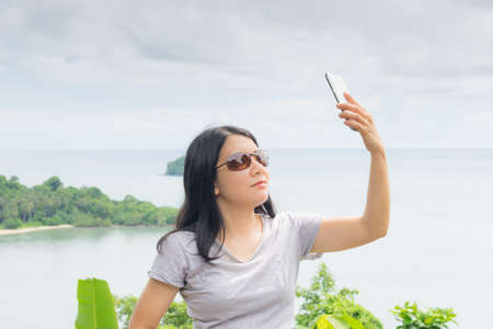 asian woman selfie with seascape against blue skyの写真素材