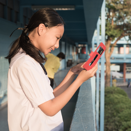 Asain high school girl play smartphone in morniing timeの写真素材