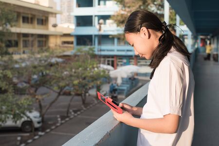 Asain high school girl play smartphone in morniing timeの写真素材