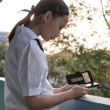 Asain high school girl play smartphone in morniing timeの写真素材