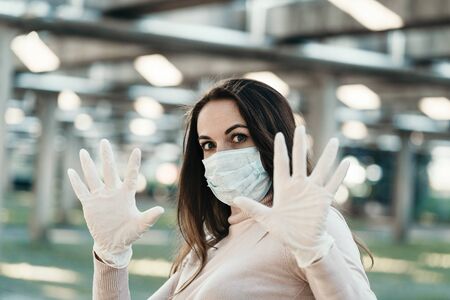 Young girl in medical mask and gloves shows stop signの写真素材