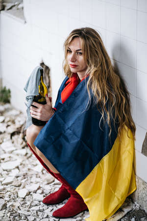 A Ukrainian woman in a ruined house. Flag of Ukraine. Stop Warの写真素材