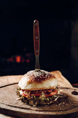 Juicy hamburger on a wooden stand on a black backgroundの写真素材