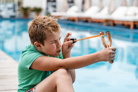 A boy shoots a slingshot near the poolの写真素材