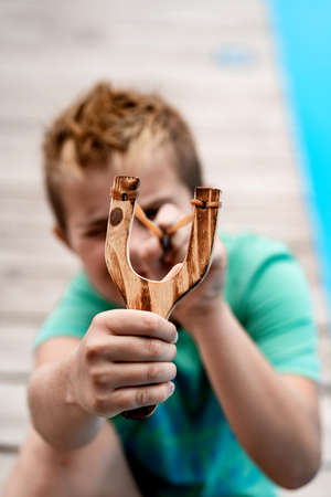 A boy shoots a slingshot near the poolの写真素材