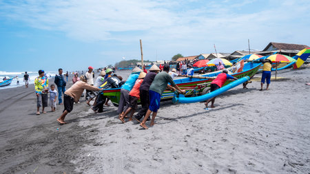 Yogyakarta, Indonesia - March 27, 2022: After returning from fishing in the sea, the fishermen push the boats to the mainlandのeditorial素材