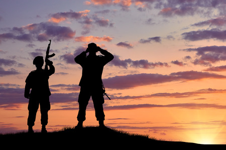 Silhouette of two soldiers on exploration at sunsetの写真素材