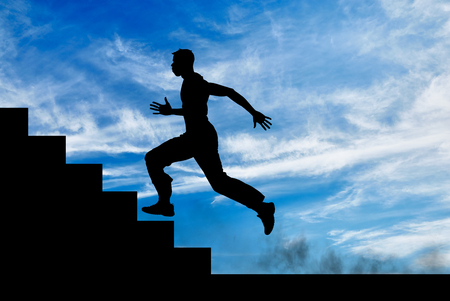 Silhouette of runner on the stairs up against the sunny skyの写真素材
