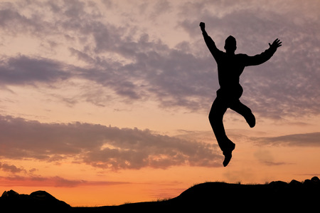 Business concept. Silhouette of a man jumping in the sunsetの写真素材