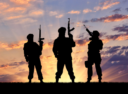 Concept of a terrorist. Silhouette terrorists with rifle at sunsetの写真素材