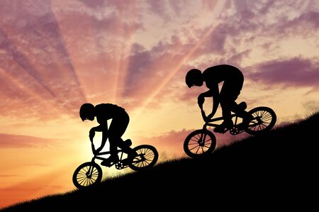 Concept of extreme sports. Silhouette of two moving cyclists at sunsetの写真素材