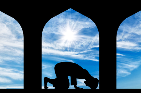 The concept of the Islamic religion. Silhouette of man praying at the Town Hallの写真素材