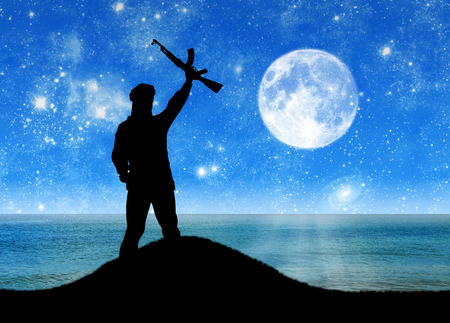 Concept of a terrorist. Silhouette of a terrorist against the sea and moonlit nightの写真素材
