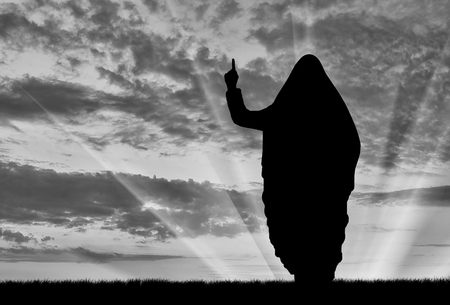 Concept of terrorism. Silhouette of a terrorist dictate their terms and conditions at sunsetの写真素材