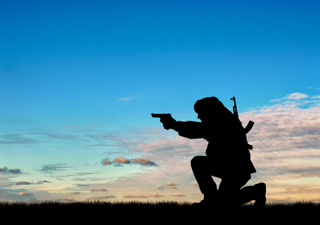 Concept of terrorism. Silhouette of a terrorist with a rifle on a background of sunsetの写真素材